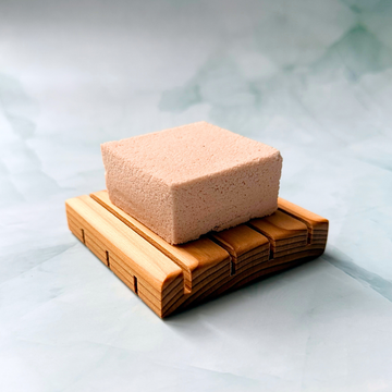 Square shower steamer on a wooden tray with a light gray background