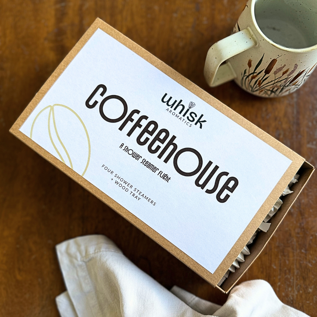 Box of 'Coffeehouse' shower steamers by Whisk Aromatics on a wooden surface with a mug.