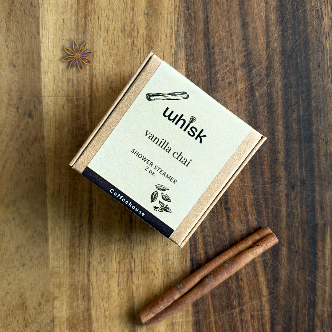 Vanilla chai shower steamer packaging on a wooden surface with a cinnamon stick.