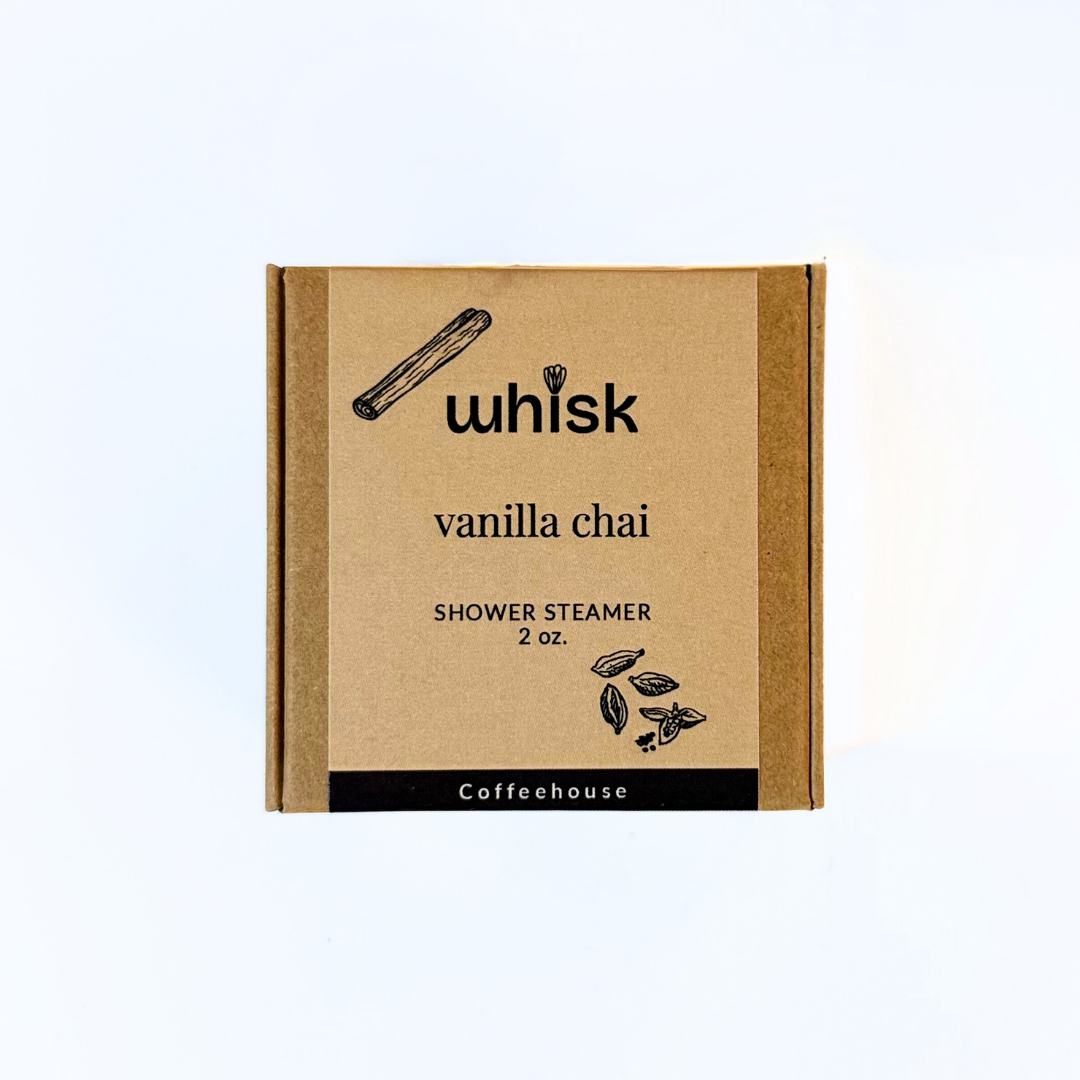 Vanilla chai shower steamer packaging on a wooden surface with a cinnamon stick.