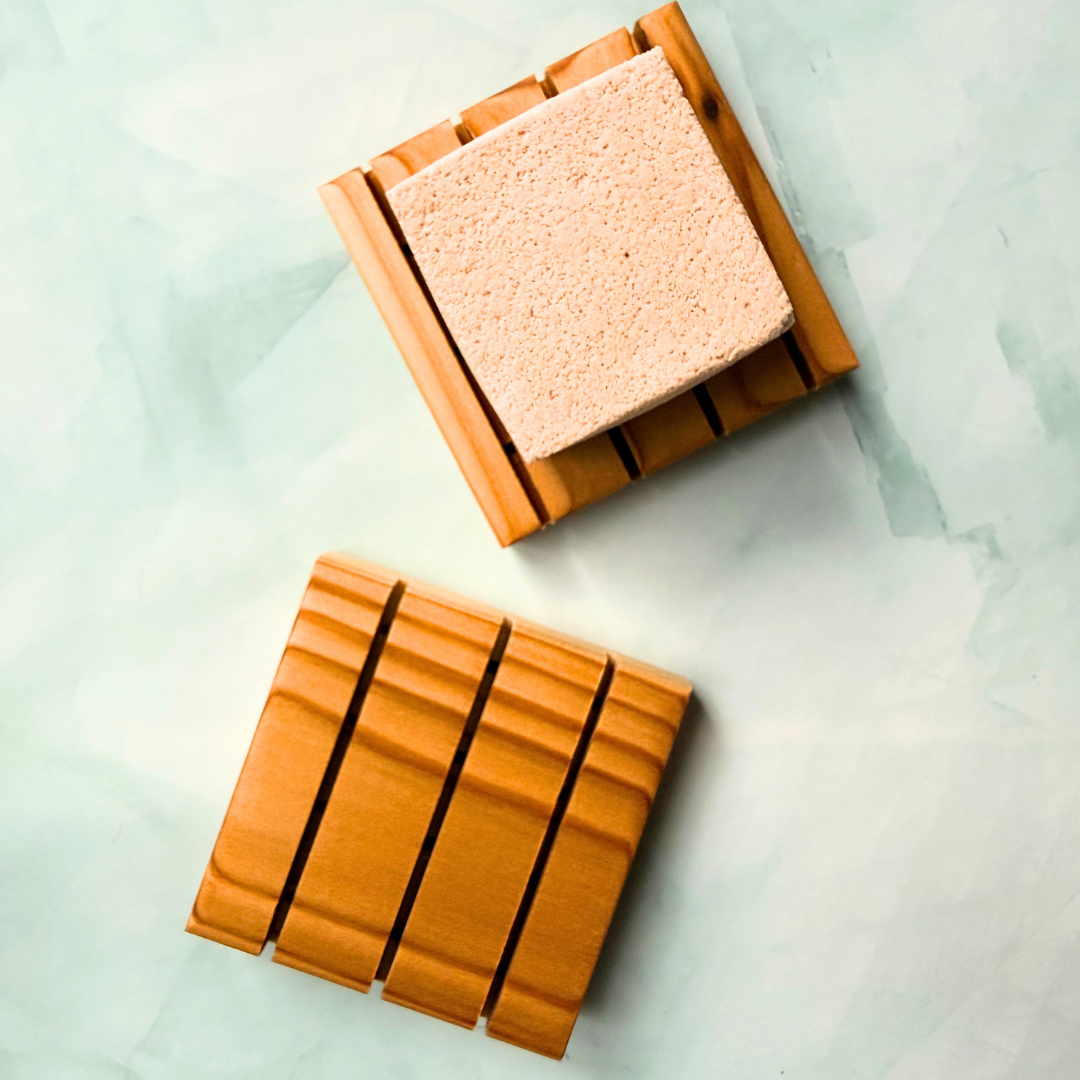 Two square wooden shower steamer trays with a textured surface on a light green marble background