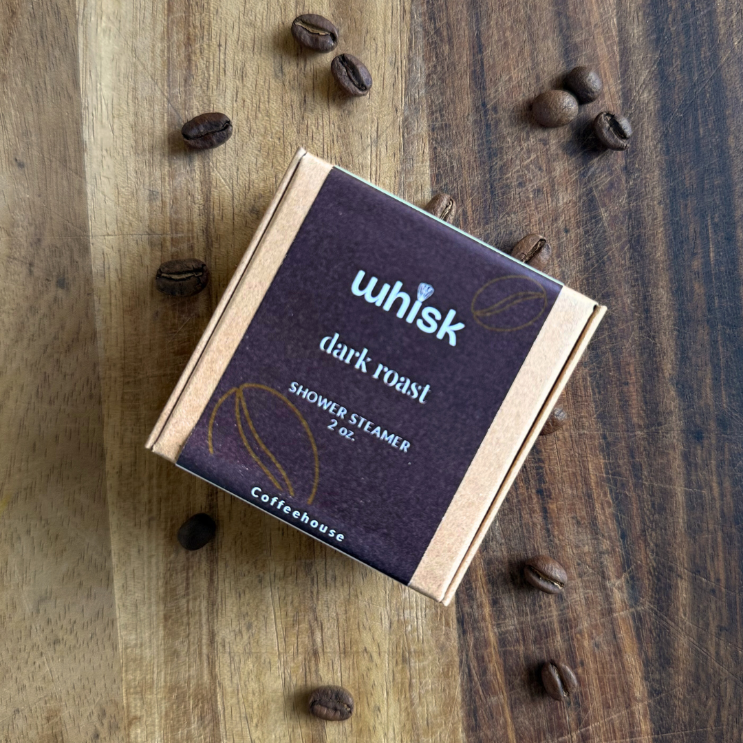 Whisk dark roast shower steamer on a wooden surface with coffee beans around