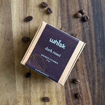 Whisk dark roast shower steamer on a wooden surface with coffee beans around