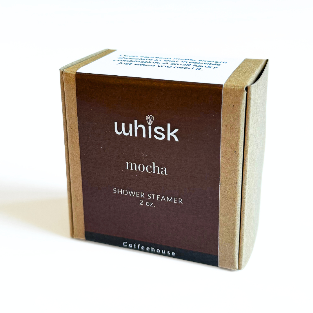 Whisk Mocha shower steamer on a wooden surface with coffee beans and chocolate pieces.