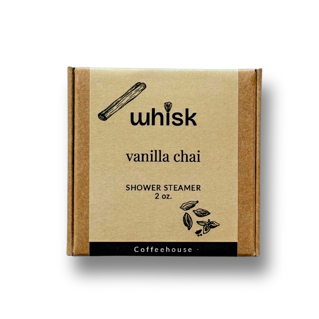 Vanilla chai shower steamer packaging on a wooden surface with a cinnamon stick.